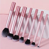 A set of ten professional makeup brushes with rose gold handles and black bristles displayed on a white box.