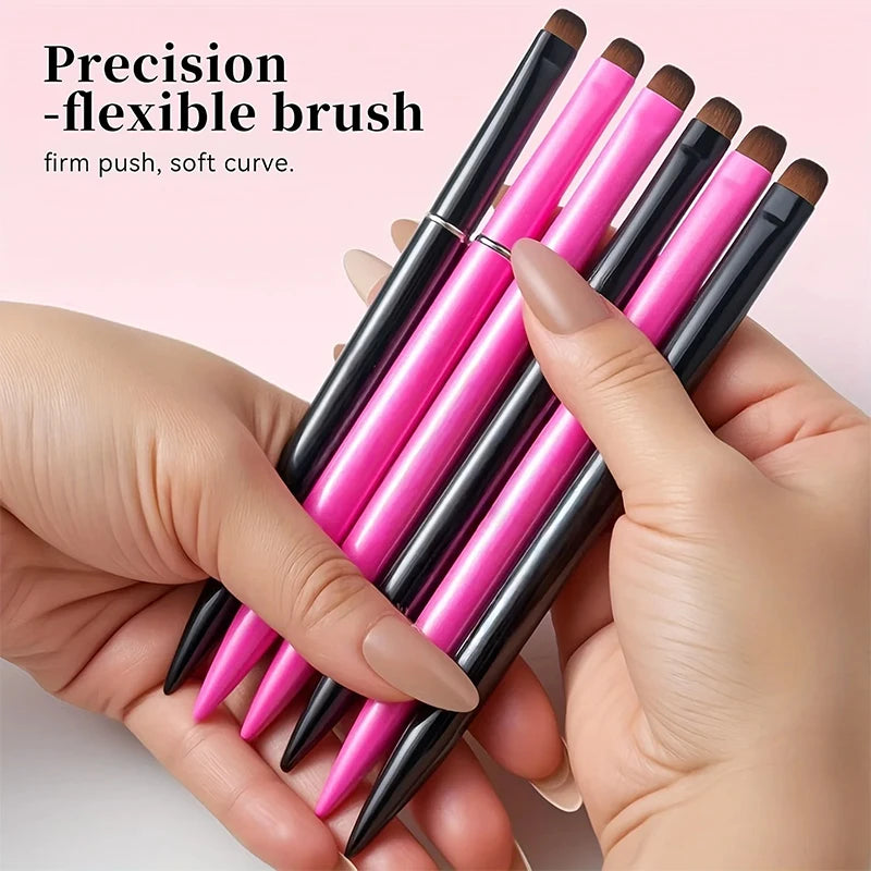 A hand holds a set of three precision flexible nail brushes with pink and black handles.