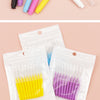 A set of precision eyebrow and lash brushes in various colors, including yellow, purple, pink, and blue, packaged in clear pl