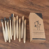 Une boîte contenant un pack de 10 brosses à dents en bambou est exposée sur une surface en bois.