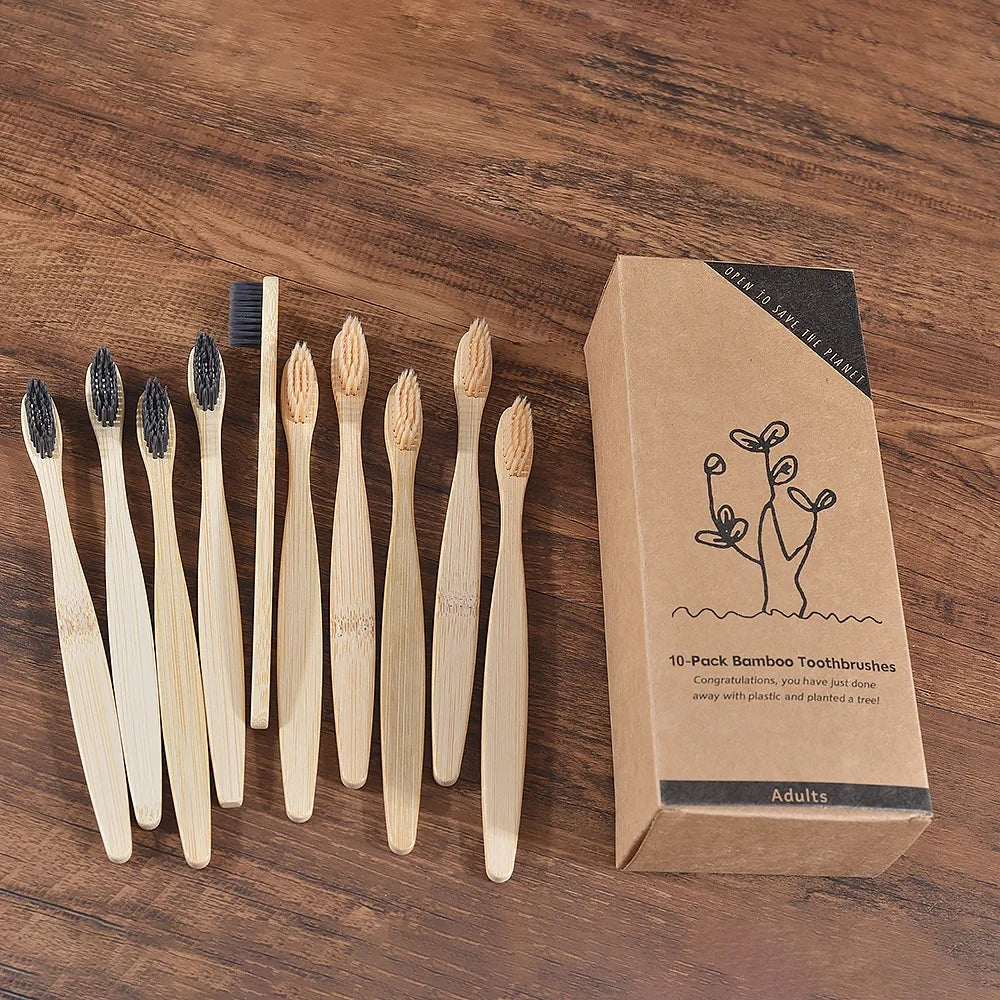 Une boîte contenant un pack de 10 brosses à dents en bambou est exposée sur une surface en bois.