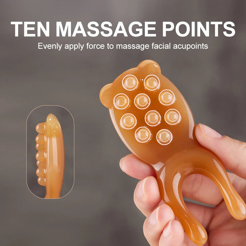 A hand holds an amber-colored facial massage tool with ten massage points for applying even force to acupoints.