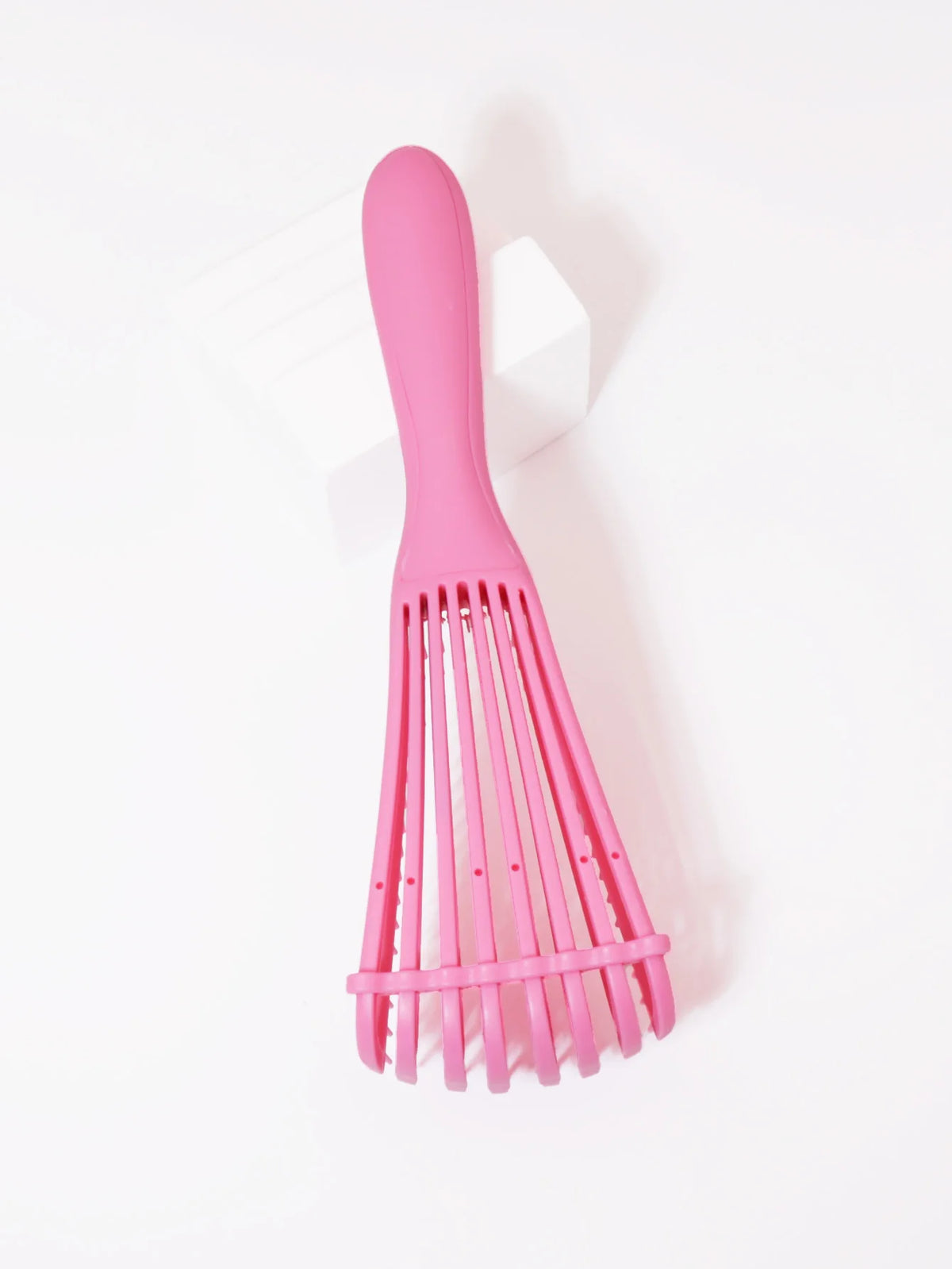 A pink adjustable detangling hair brush with multiple flexible bristles is shown against a white background.