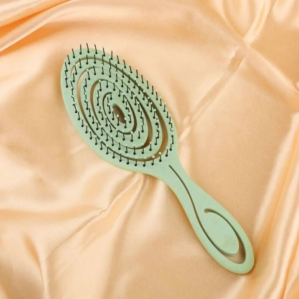 Un peigne de couleur vert clair aux dents arrondies posé sur un tissu satiné couleur pêche.