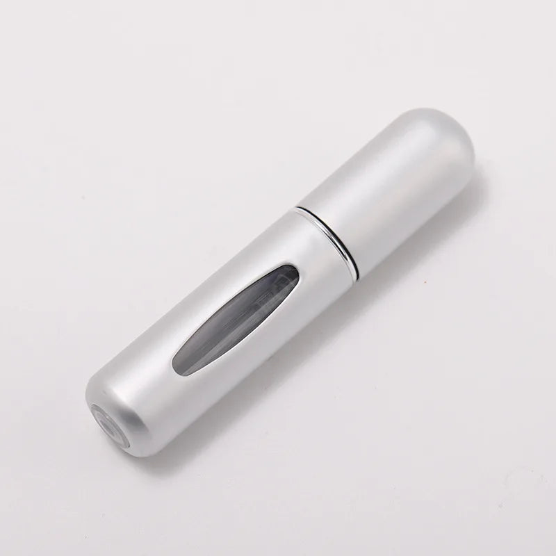 A silver portable refillable perfume bottle with a clear glass insert, shown in a profile view.