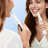 A woman is using an electric dental scaler device on another woman's teeth.