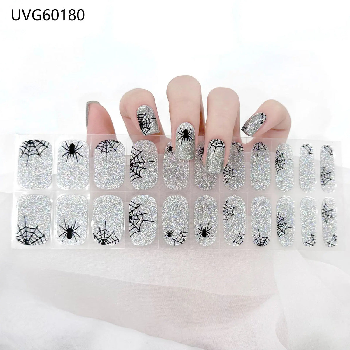 UV gel nail stickers featuring black and silver spiders and webs applied to fingernails.