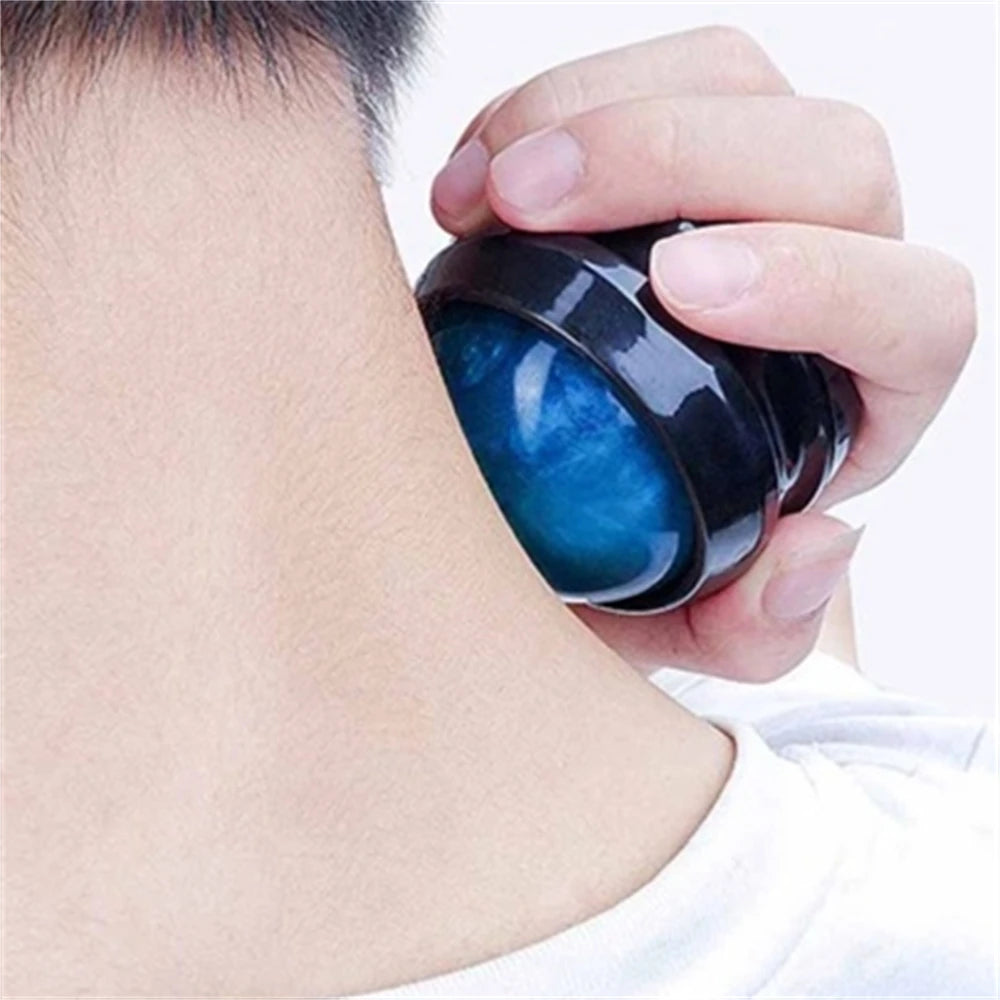 A hand holds a dark massage ball with a glowing blue interior against a person's neck.