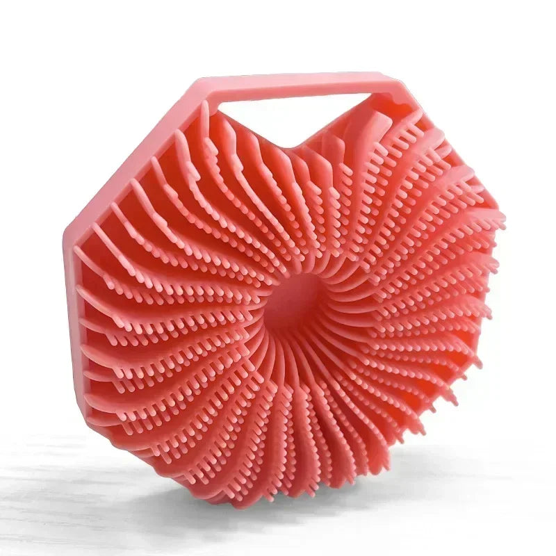 A pink silicone exfoliating shower scrub brush with a textured, fan-like surface.