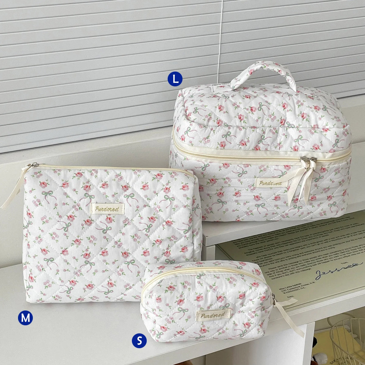 Three quilted white cotton makeup bags of different sizes are displayed on a white surface.