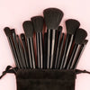 A set of black makeup brushes with sponge heads arranged on a pink background.