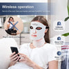 A woman is wearing a white LED facial mask while using a smartphone.