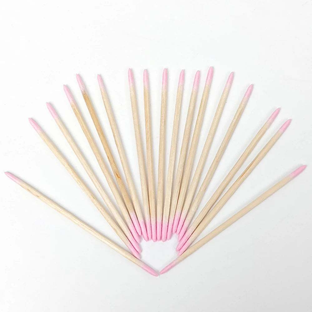 Arrangement de bâtonnets en bois fins avec des pointes roses, disposés en forme de V.