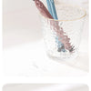 Une tasse en verre contient un jeu de trois brosses à dents en bois et bleues.