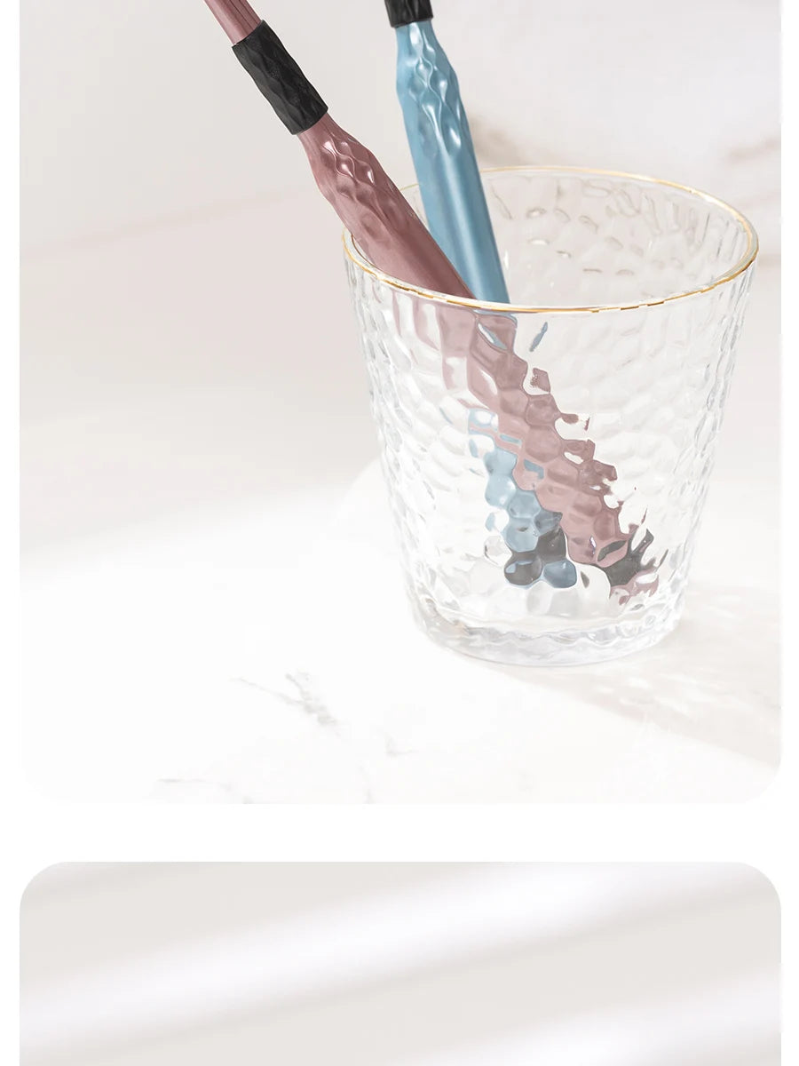 Une tasse en verre contient un jeu de trois brosses à dents en bois et bleues.