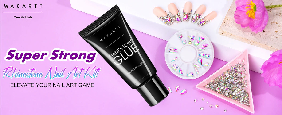 A black tube of Super Strong Rhinestone Glue for nail art is displayed next to loose rhinestones and pink flowers.