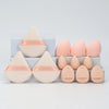 A set of twelve pink and peach-colored makeup sponges arranged on a white display box.