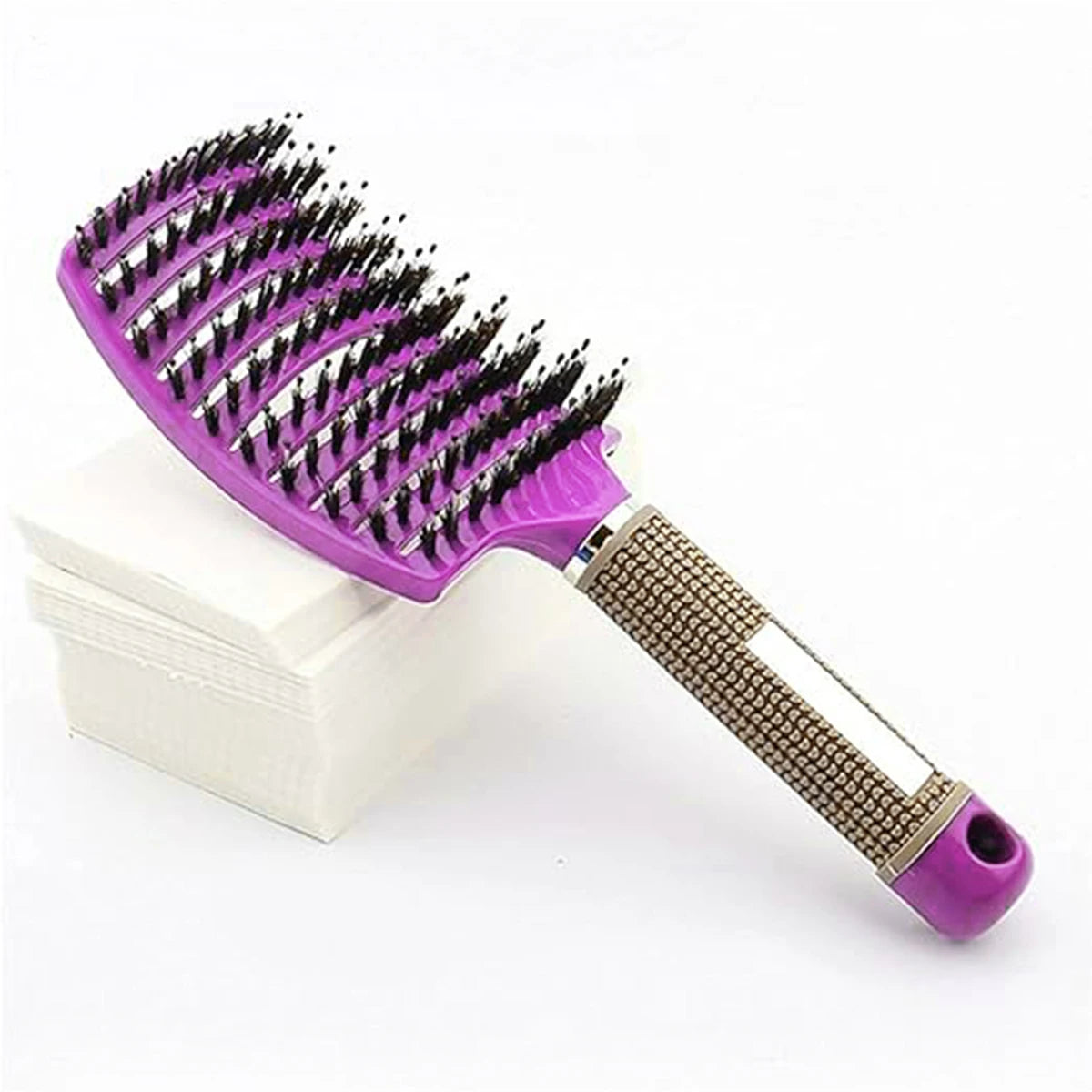 Piel de jabalí morada para masaje y peine de cabello sobre una superficie blanca.