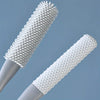 A close-up view of a white, long-handled manual foot scrubber with dense bristles and a smooth handle.