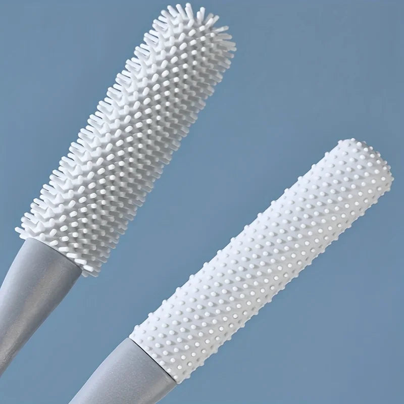 A close-up view of a white, long-handled manual foot scrubber with dense bristles and a smooth handle.