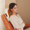 A woman is using a portable shiatsu neck massager pillow on her shoulder, demonstrating the heat compress feature.