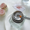 A close-up of a clear glass bottle with a silver pump dispenser and a brush, demonstrating a push-type water outlet design.