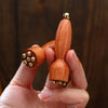 A hand holds a wooden gua sha tool with brass accents for facial massage.