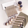 A set of professional makeup brushes with gold and silver handles and fluffy bristles displayed on a neutral background.