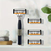 A black multi-blade safety razor with orange accents is displayed on a white surface.