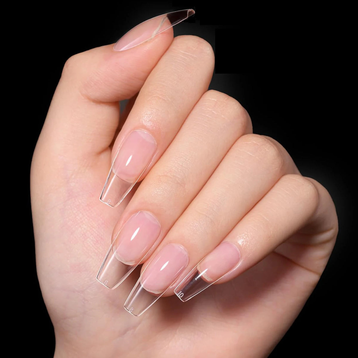 Une main tient un ensemble d'ongles pressions transparents de différentes formes et tailles.