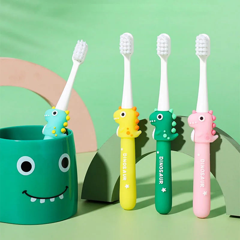 A set of pink, yellow, and green cartoon dinosaur toothbrushes with white bristles displayed on a light green background.