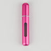 A sleek, cylindrical pink portable refillable perfume bottle with a silver band and a dark inner section.
