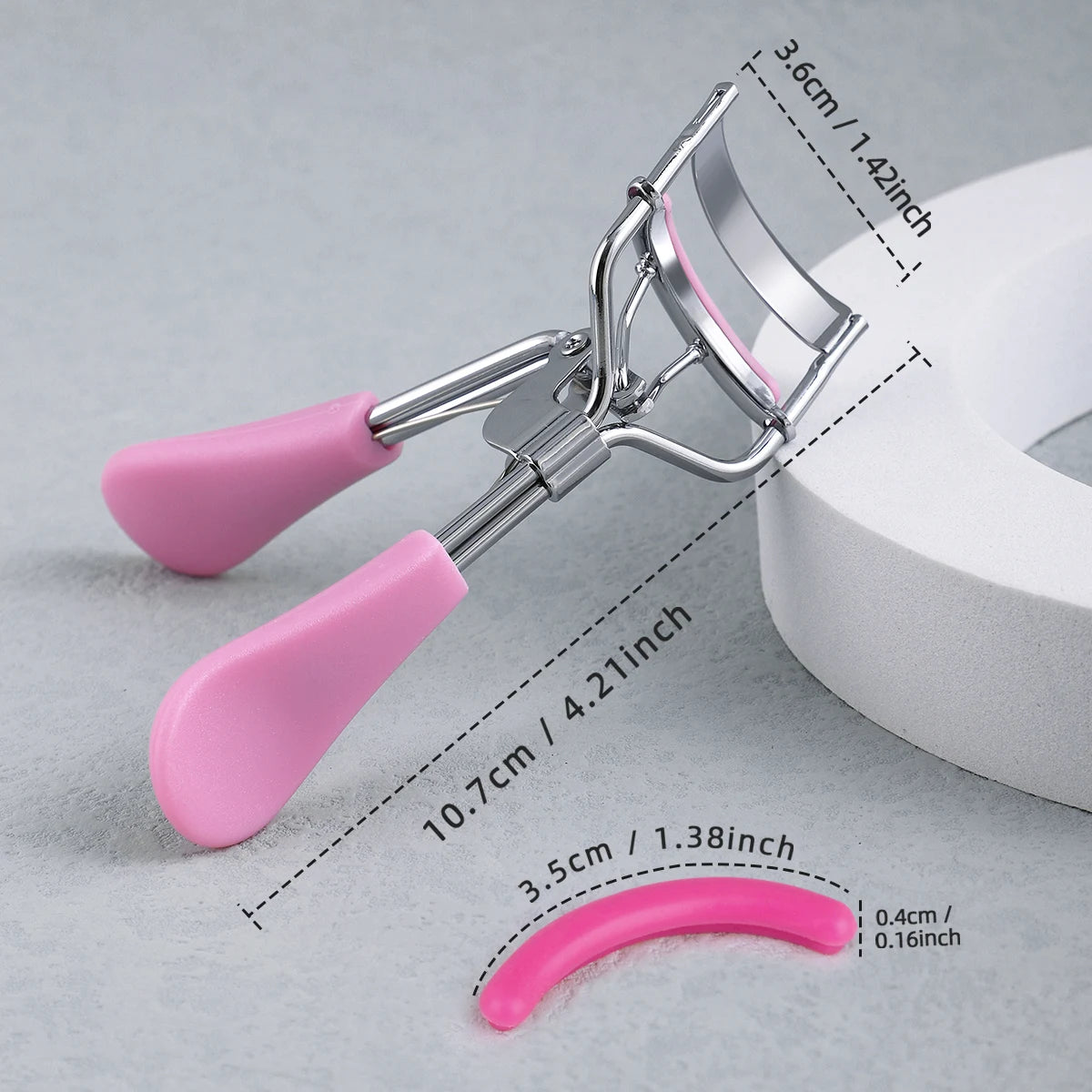 A professional stainless steel eyelash curler set with pink handles and a curved tool shown on a gray background.