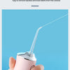 A hand holds a pink portable water flosser with a clear tube, demonstrating its fine water flow for dental cleaning.
