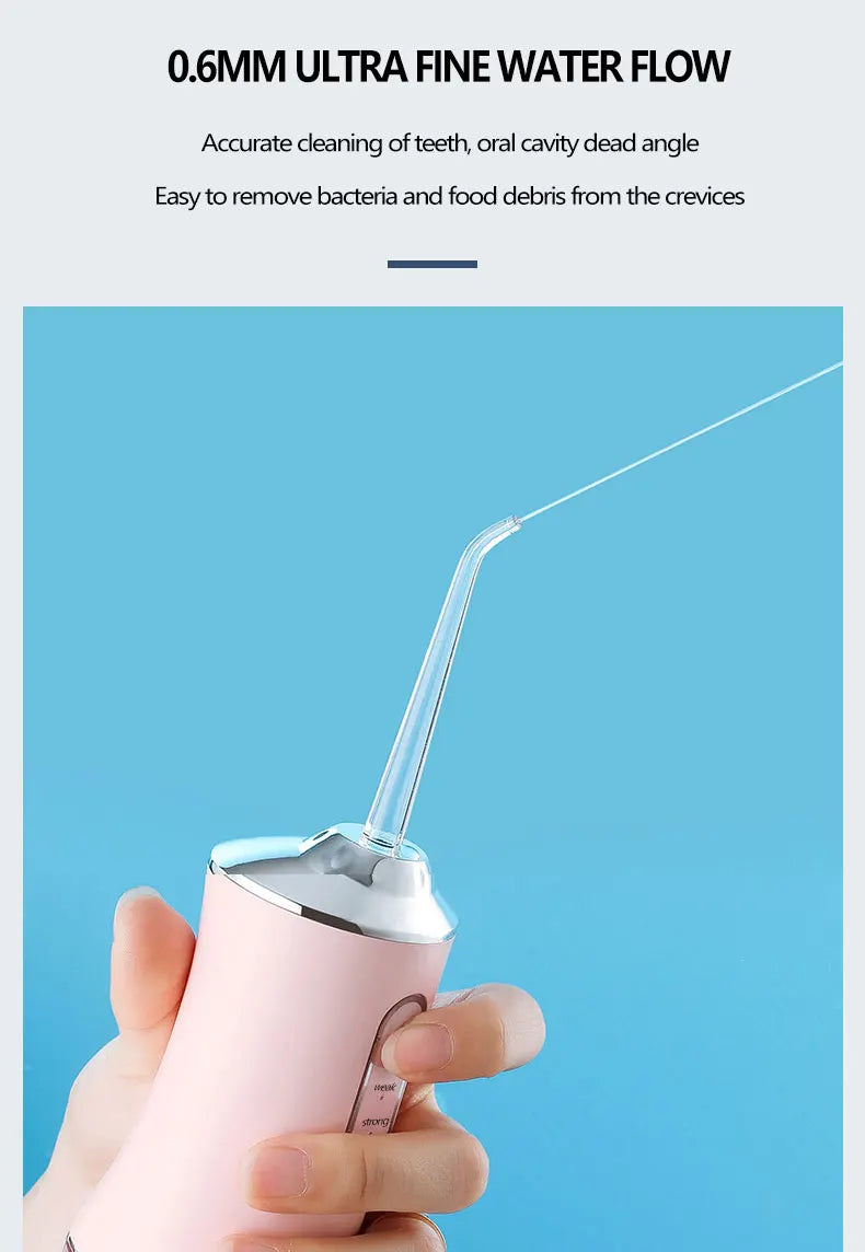 A hand holds a pink portable water flosser with a clear tube, demonstrating its fine water flow for dental cleaning.