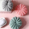 Three exfoliating bath bubble balls in shades of gray, pink, and mint green with soft mesh sponges.