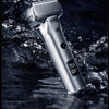 A silver portable electric shaver is shown dripping water in a dark, wet environment.
