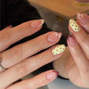 Close-up of a hand displaying reusable press-on nails with an almond shape featuring pink and red polka dots.