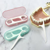A set of portable teeth flosser cleaning sticks in pink and teal colors resting on a white marble surface.