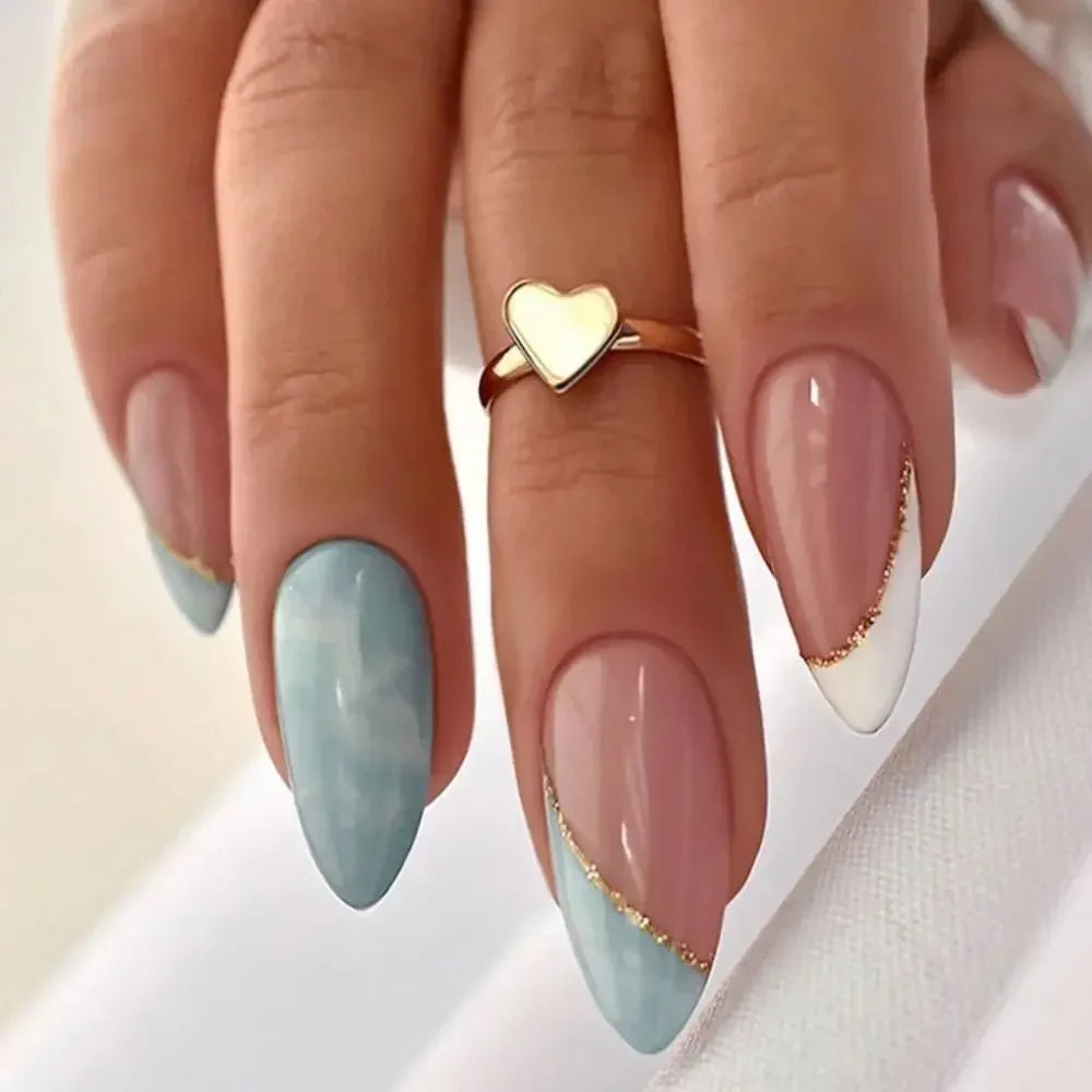 A hand displays press-on false nails with a French wavy design featuring light blue and white accents.
