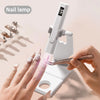 A hand applies gel polish under a portable UV nail lamp with an LCD display to a fingernail.