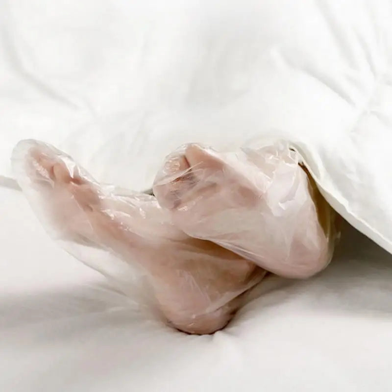 Une paire de chaussettes hydratantes pour les pieds jetables posées sur une surface blanche.