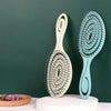 Peigne de coiffure en silicone bleu clair avec manche blanc, sur fond vert foncé.
