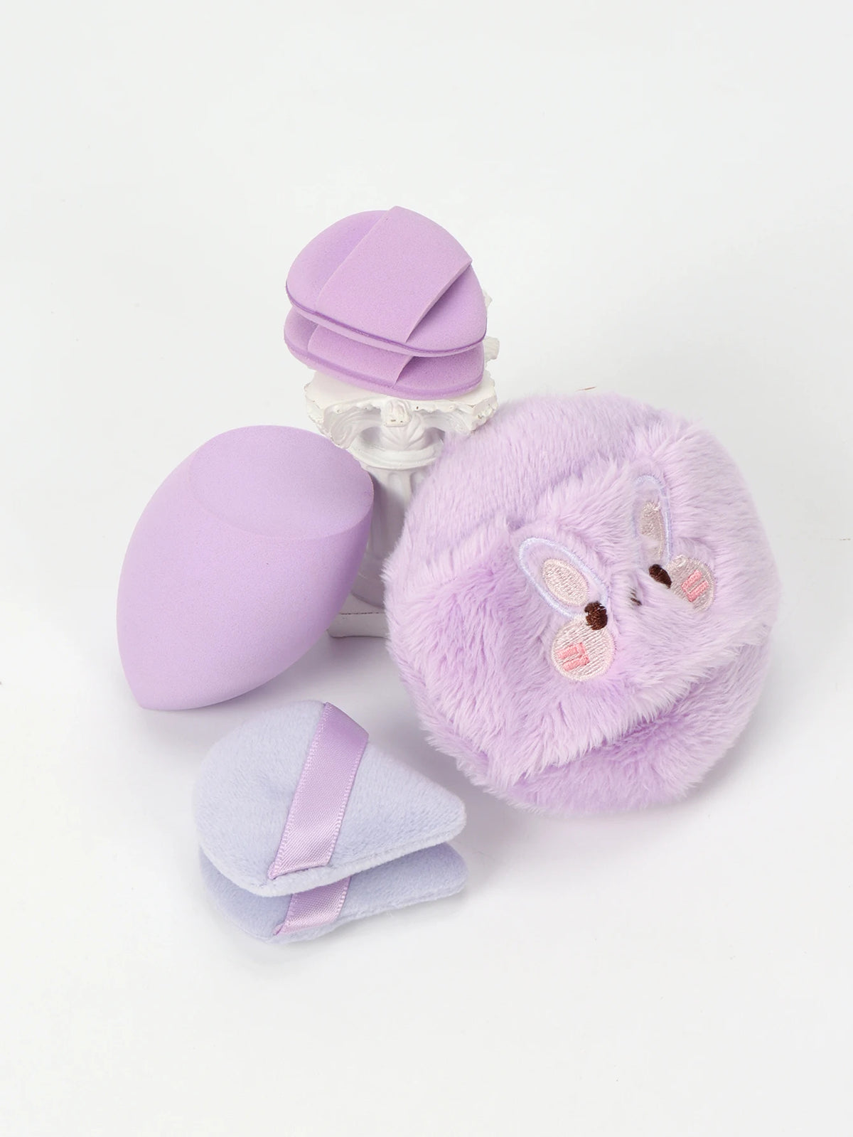 Un set de poudres légères violettes et lavande, comprenant un puff rond violet et un puff de lavande duveteux.