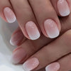 Close-up of a hand displaying French style press-on nails with sheer pink and white gradient finish
