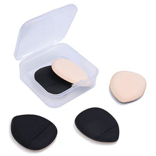 Un contenant en plastique transparent avec une éponge de fond de teint rose pâle et deux éponges de fond de teint noires.