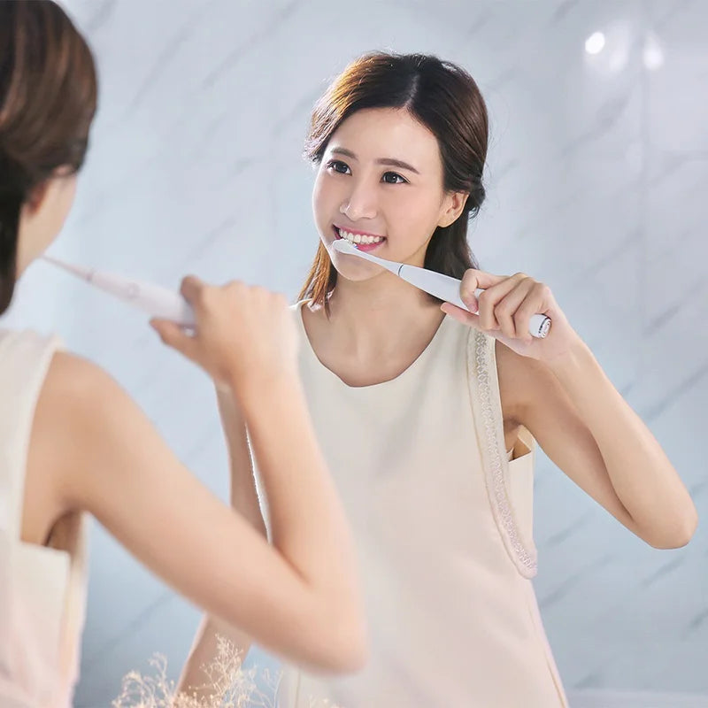 A woman is shown using replacement bristles on a sonic toothbrush.