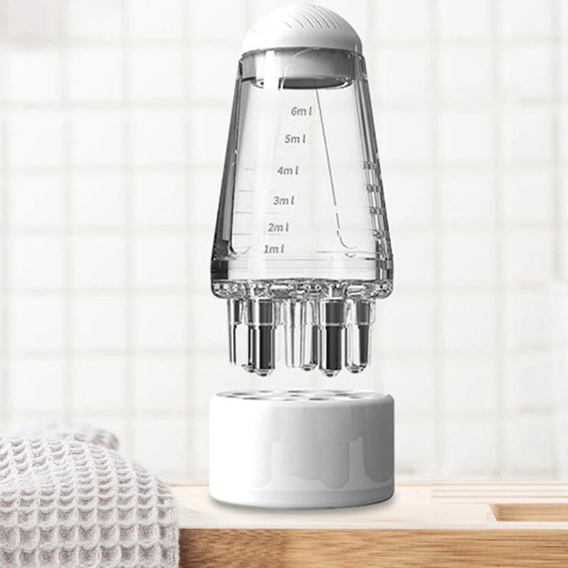 A clear glass portable scalp applicator with multiple dropper tips for applying serums and oils.