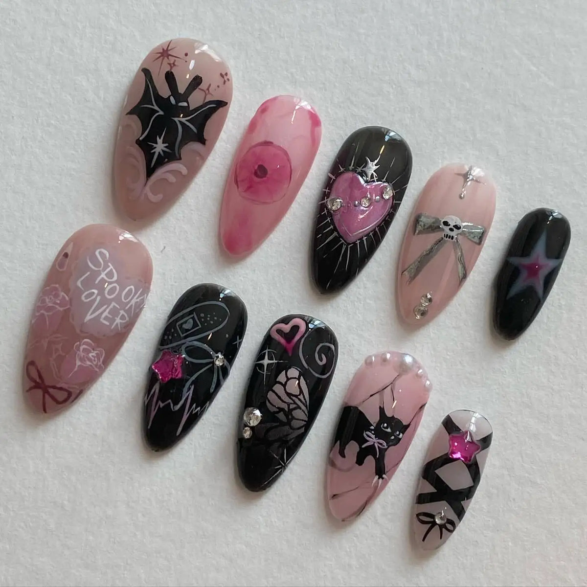 A collection of 24 press-on fake nails featuring pink and black designs with heart and spider motifs.