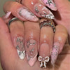 Nahaufnahme einer Hand, die elegante, durchscheinende rosa und weiße Press-on-Falschnägel mit silbernem Glitzer zeigt.